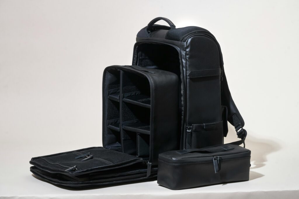 pexels-photo-842959-842959 Sleek black leather camera bag showcasing compartments on a white background.